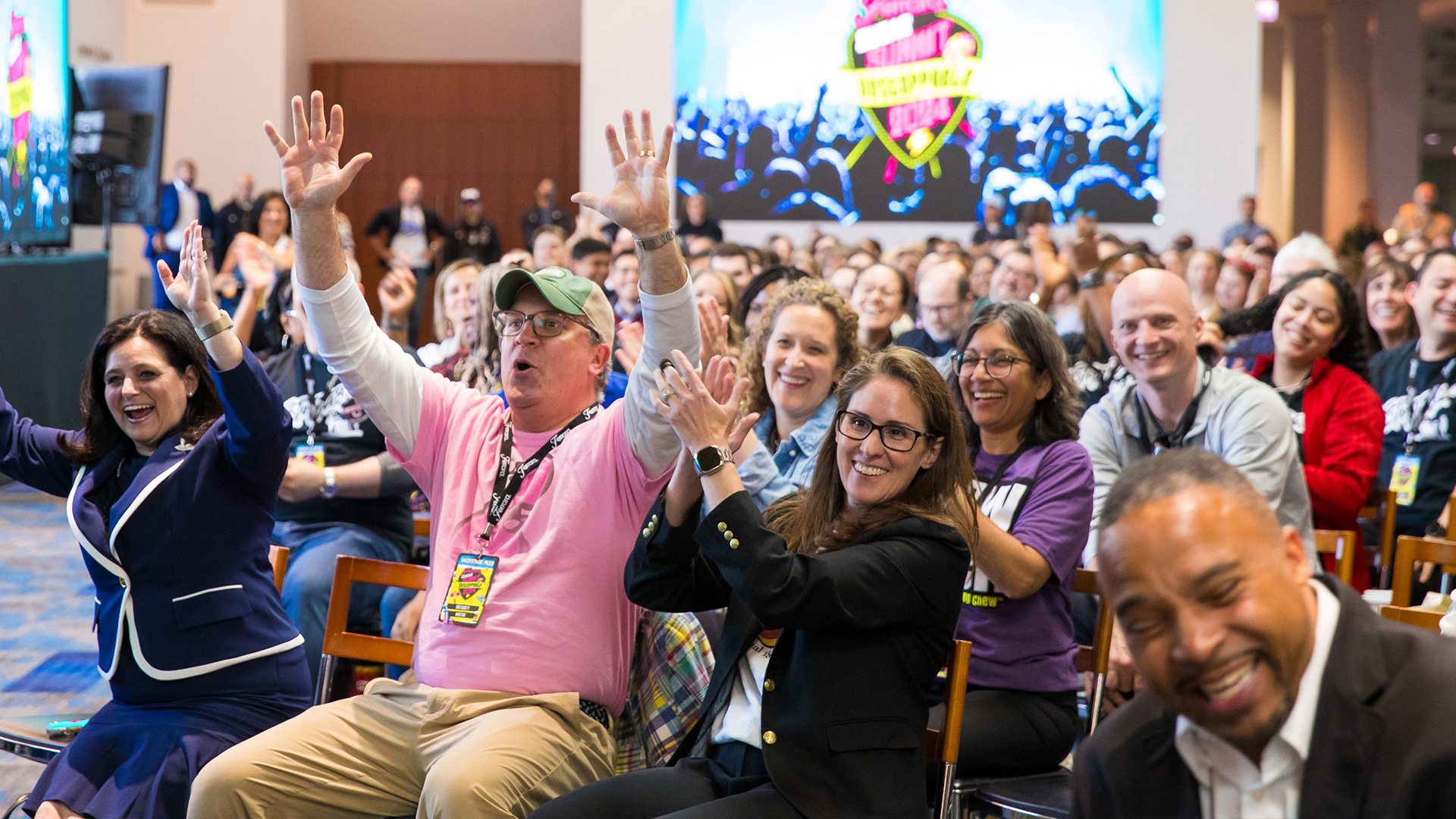 Group of employees sitting down and cheering at a company wide event